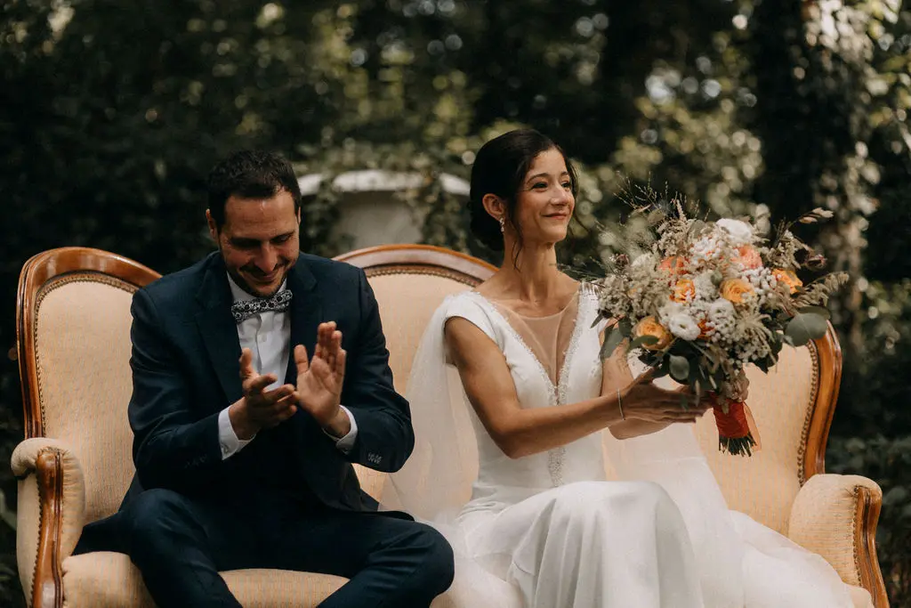 Un couple de mariés pendant leur cérémonie laïque, au Château de Chavagnac en Rhône-Alpes. La mariée est très élégante et sa mise en beauté est sophistiquée.