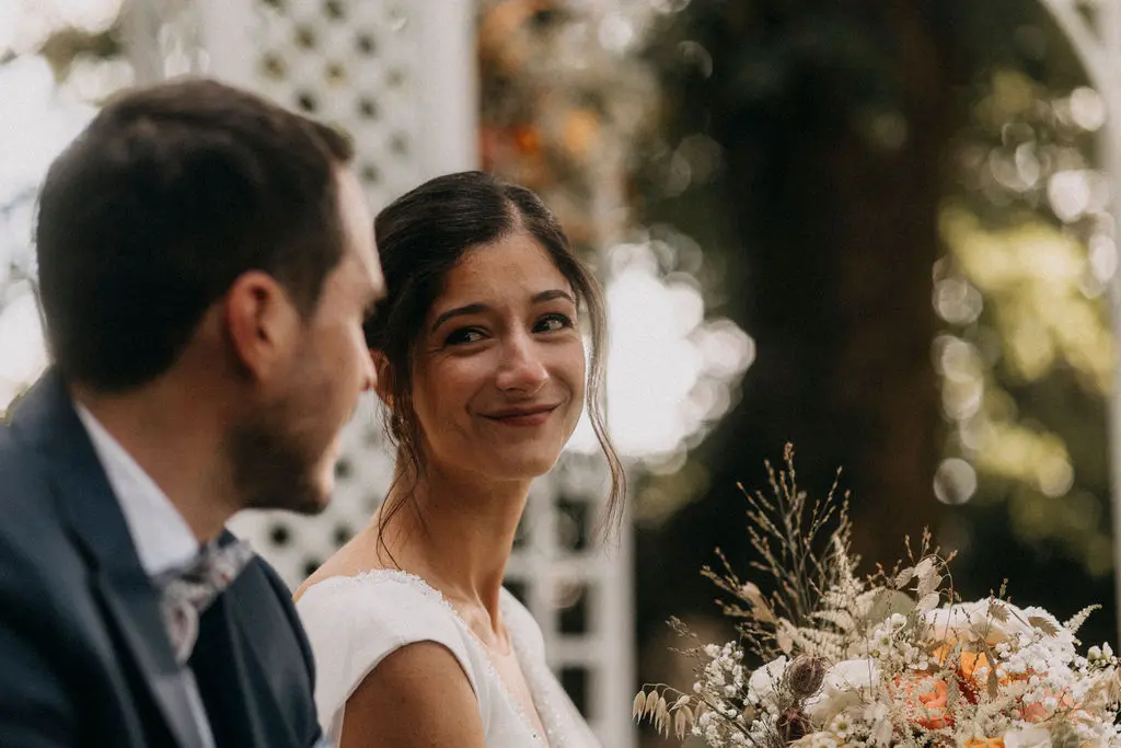 Mari et femme se regardent dans les yeux durant leur cérémonie. Ils sont très émus des discours prononcés par leurs proches. La mariée porte un rouge à lèvres rosé.